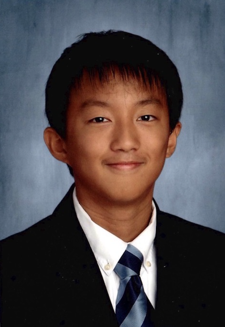Kyson Zhou, smiling, wearing a jacket and tie