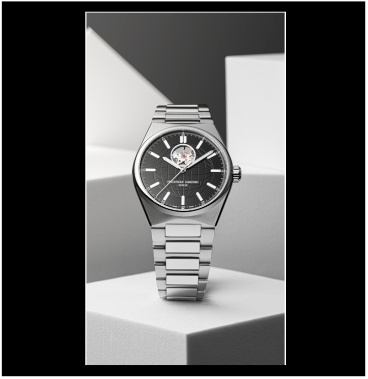 A men's watch by Frederique Constant. The watch is silver in color, with a black face. The background of the image is abstract blocks in black, white, and gray.