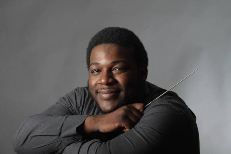 Kenneth Bean, smiling and leaning his chin on his hand, holding a conductor's baton