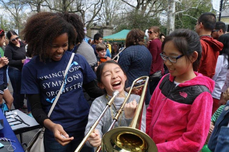 Little girl smiling holding a trombone with two girls standing next to her.