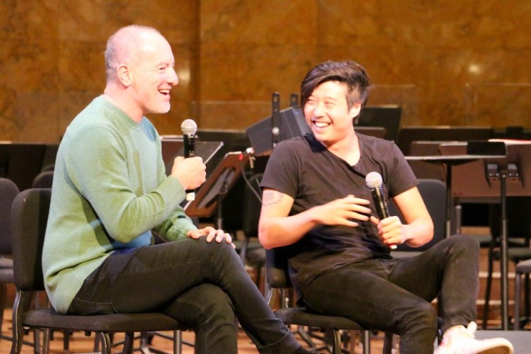 Two people chatting on stage and smiling, both holding microphones.