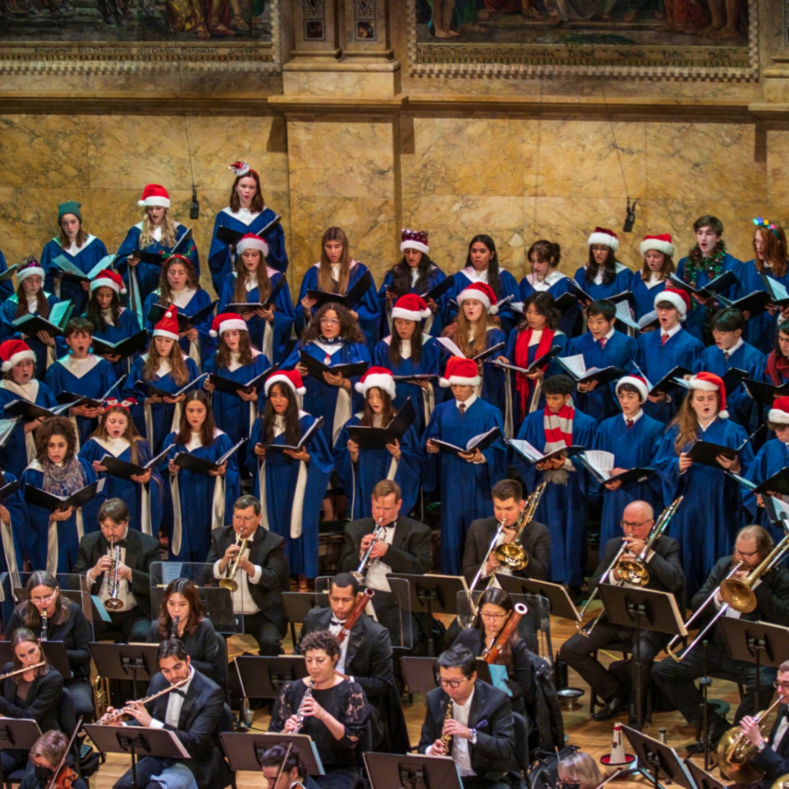Choir in blue robes and holiday accessories singing onstage 