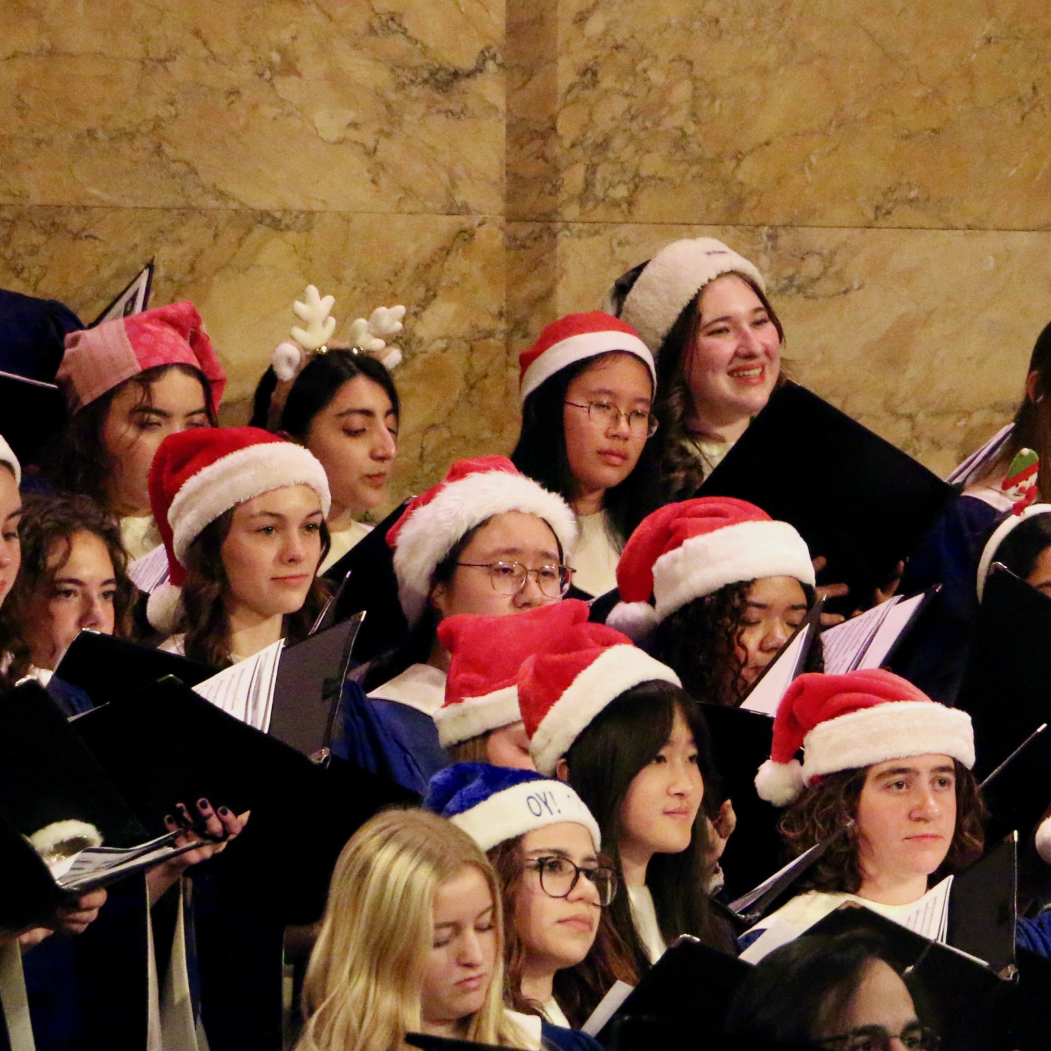 Holiday POPS! choir members performing in choir robes and Santa hats.