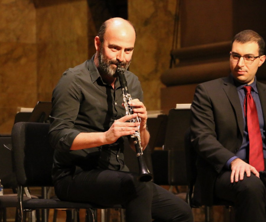 Kinan Azmeh and Saad Haddad seated onstage. Kinan Azmeh is playing the clarinet.