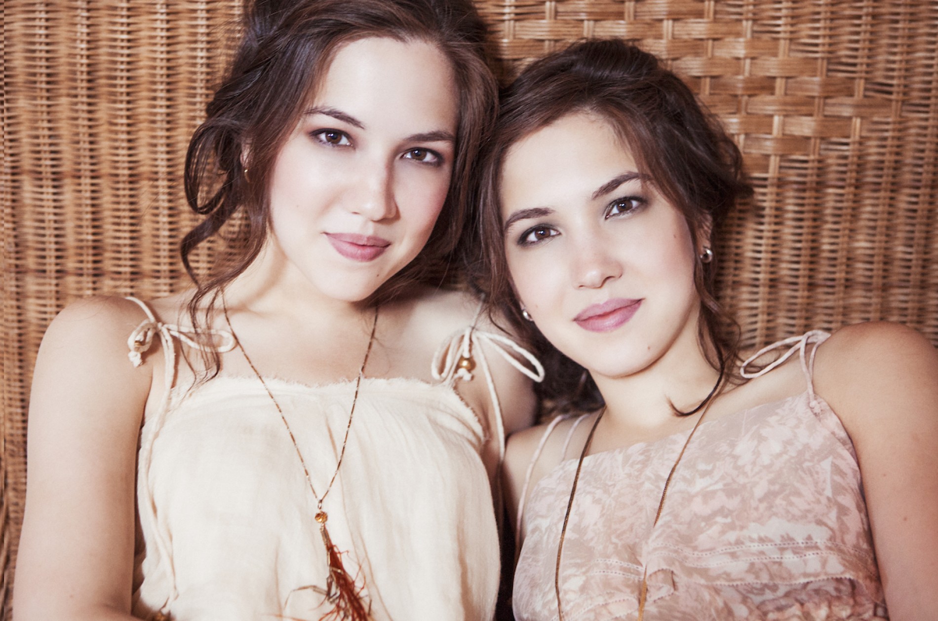 Christina and Michelle Naughton pose against a wicker background wearing sundresses