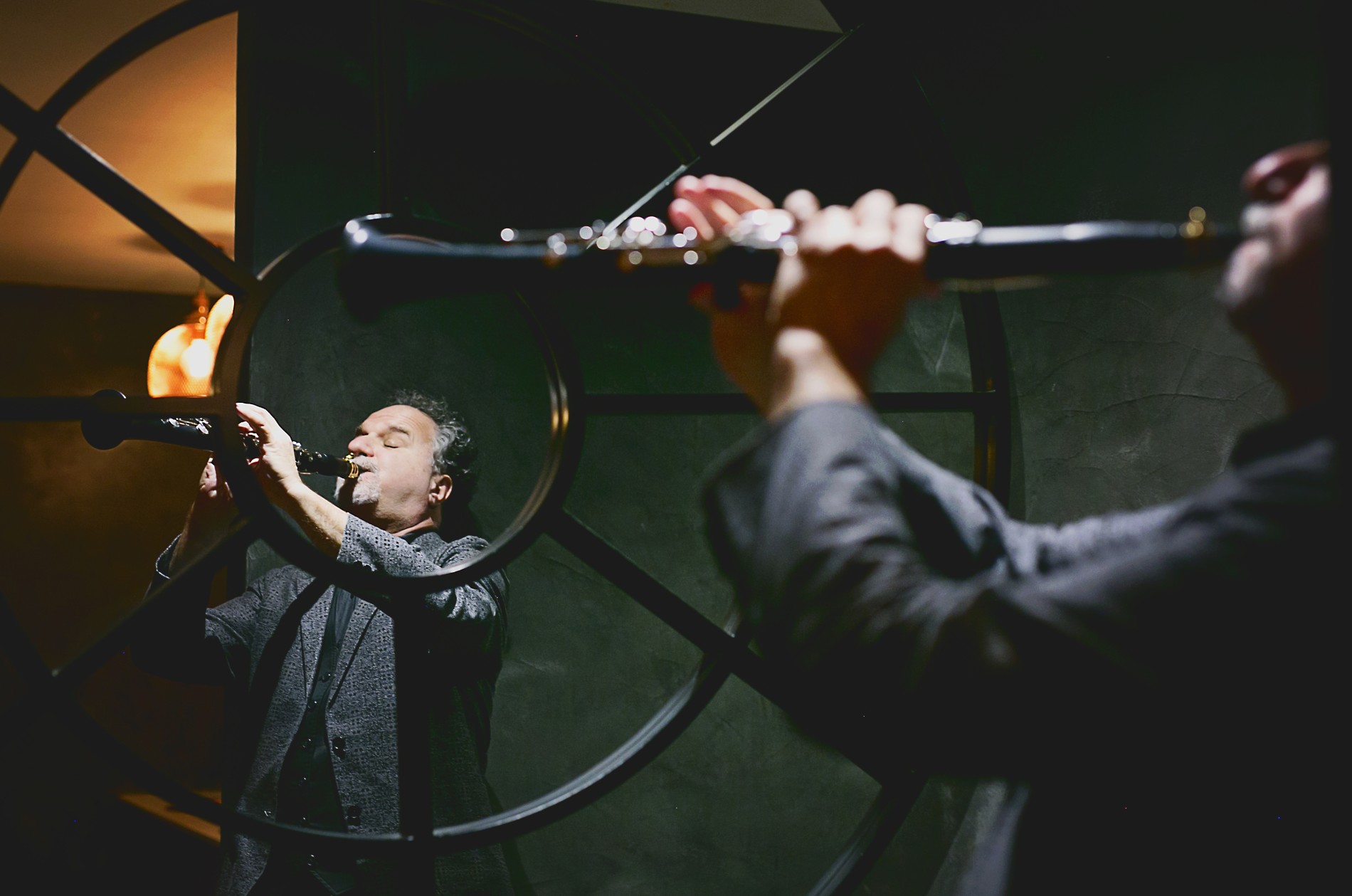 Reflection of a man playing clarinet in a round, paned mirror